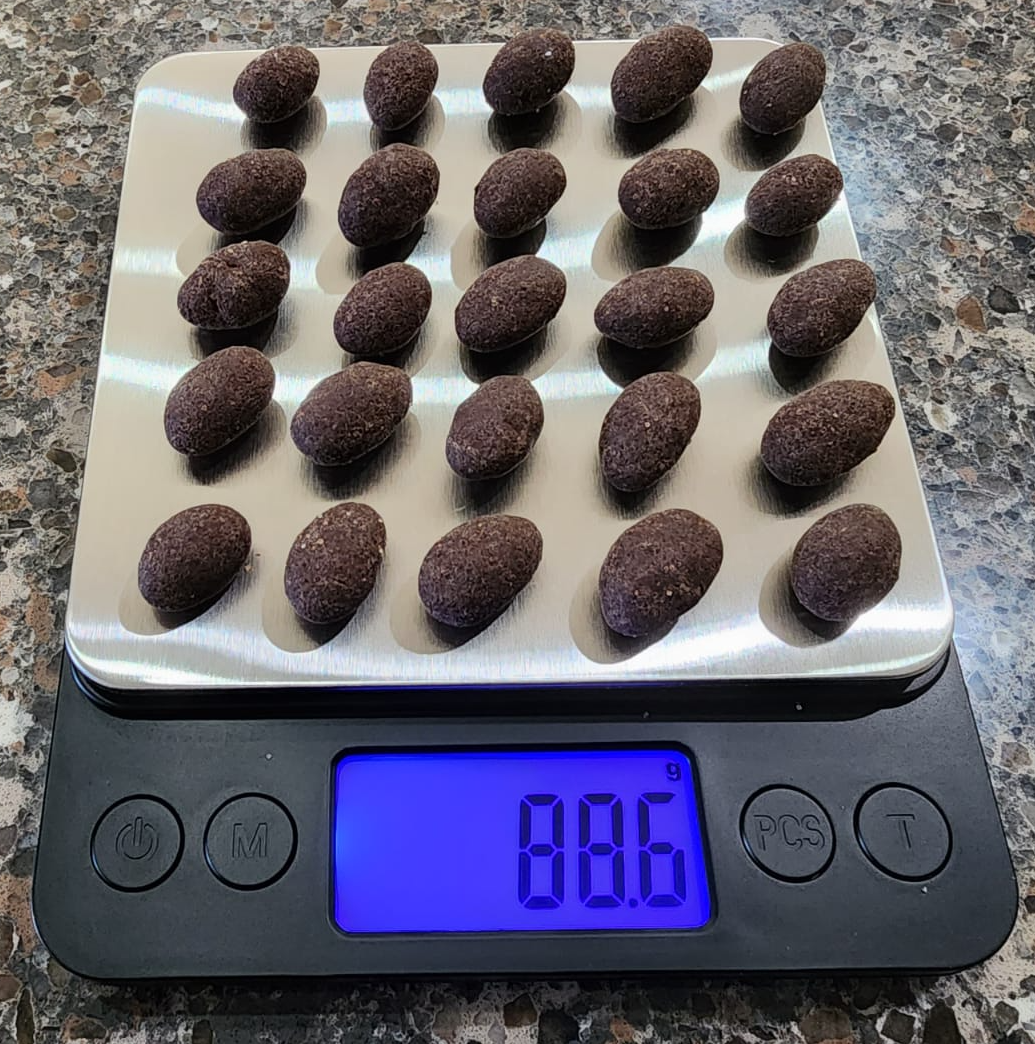 A random sample of 25 chocolate-covered almonds on a digital scale showing the total weight.