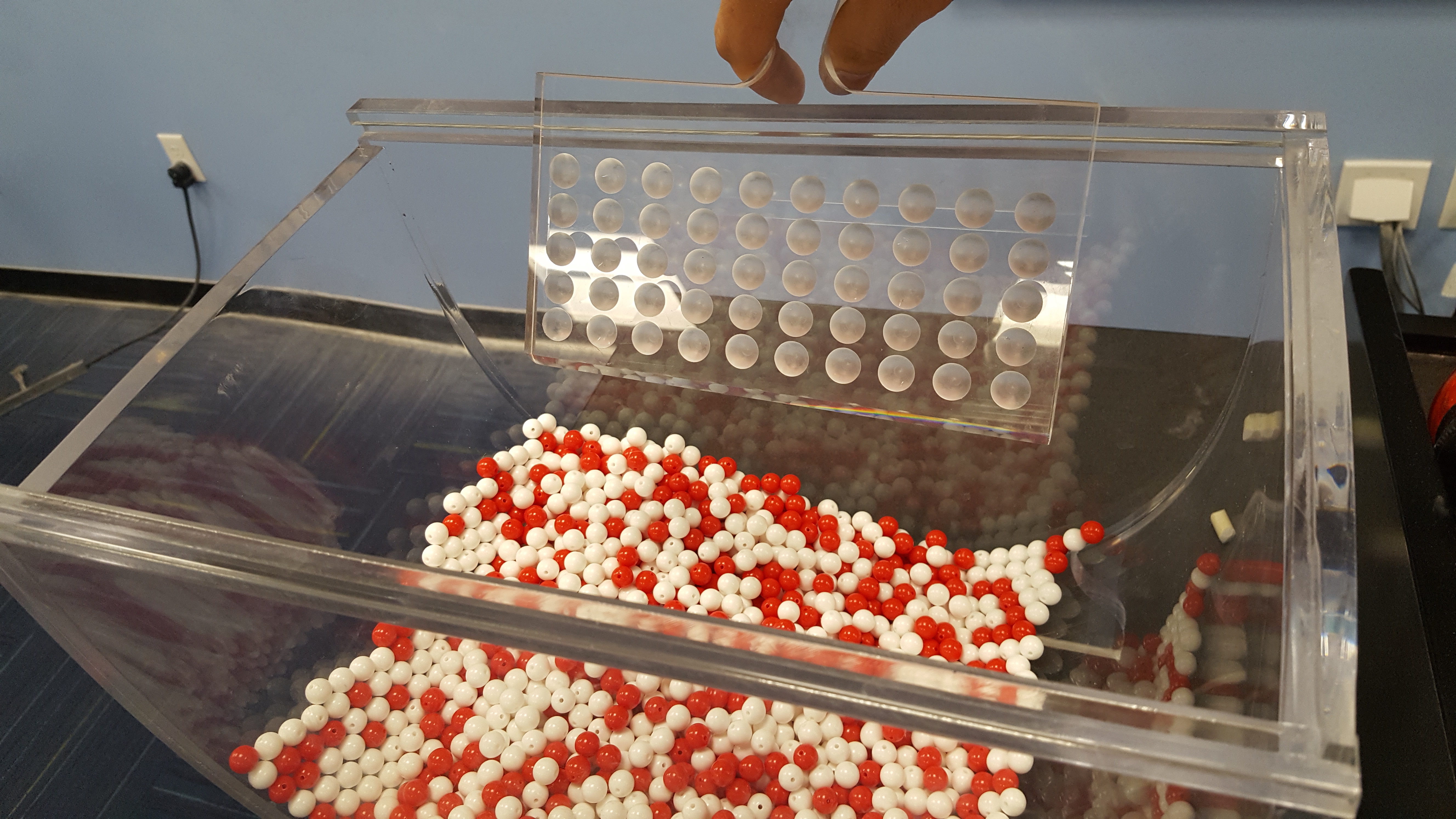 A shovel being inserted into a bowl of red and white balls.