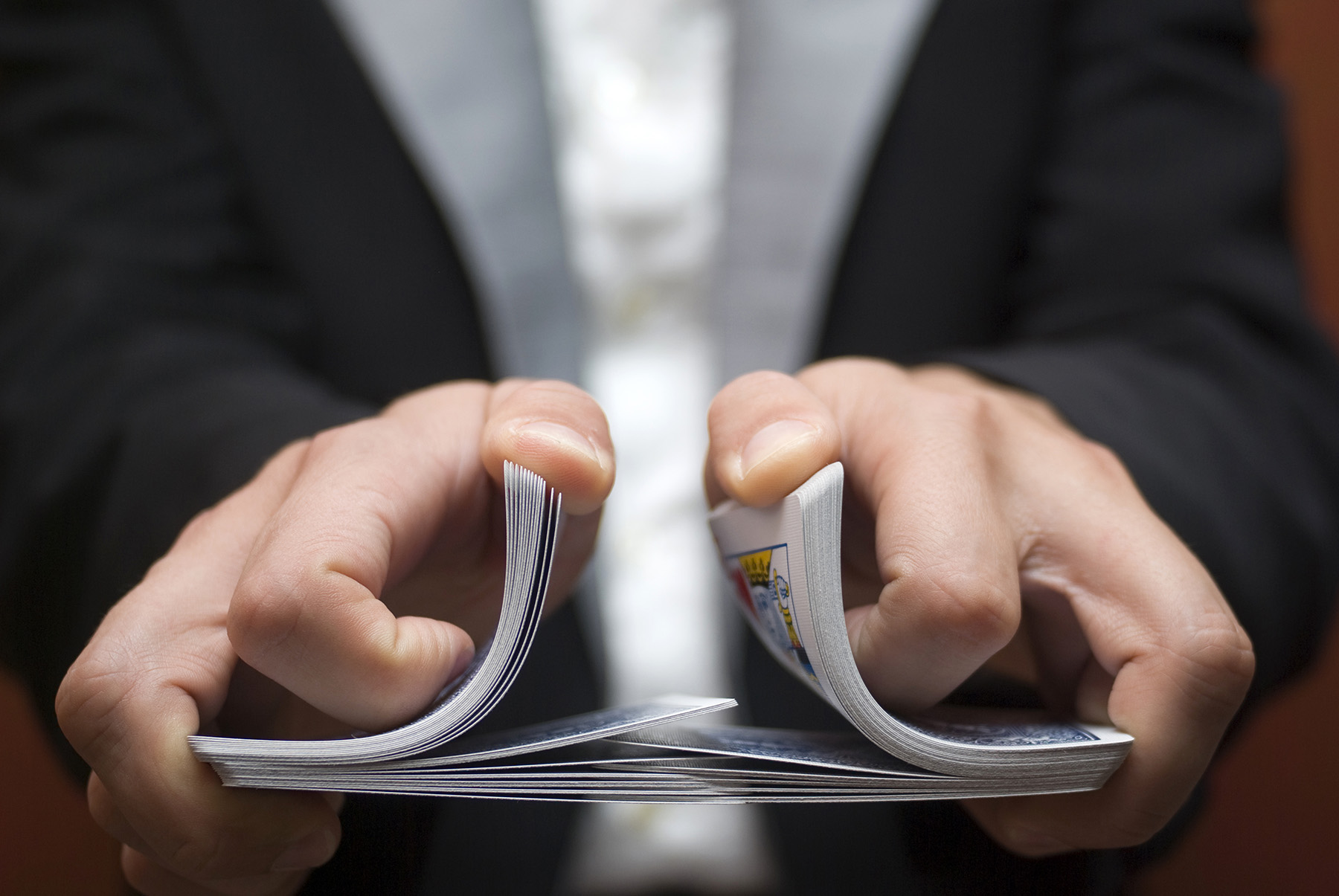 A person’s hands shuffling a deck of playing cards.