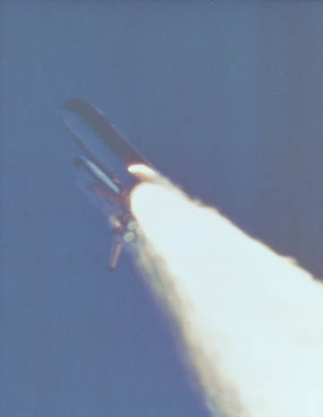 A photograph of the Space Shuttle Challenger’s solid rocket booster with a small flame visible on its side, indicating the O-ring failure that led to the explosion